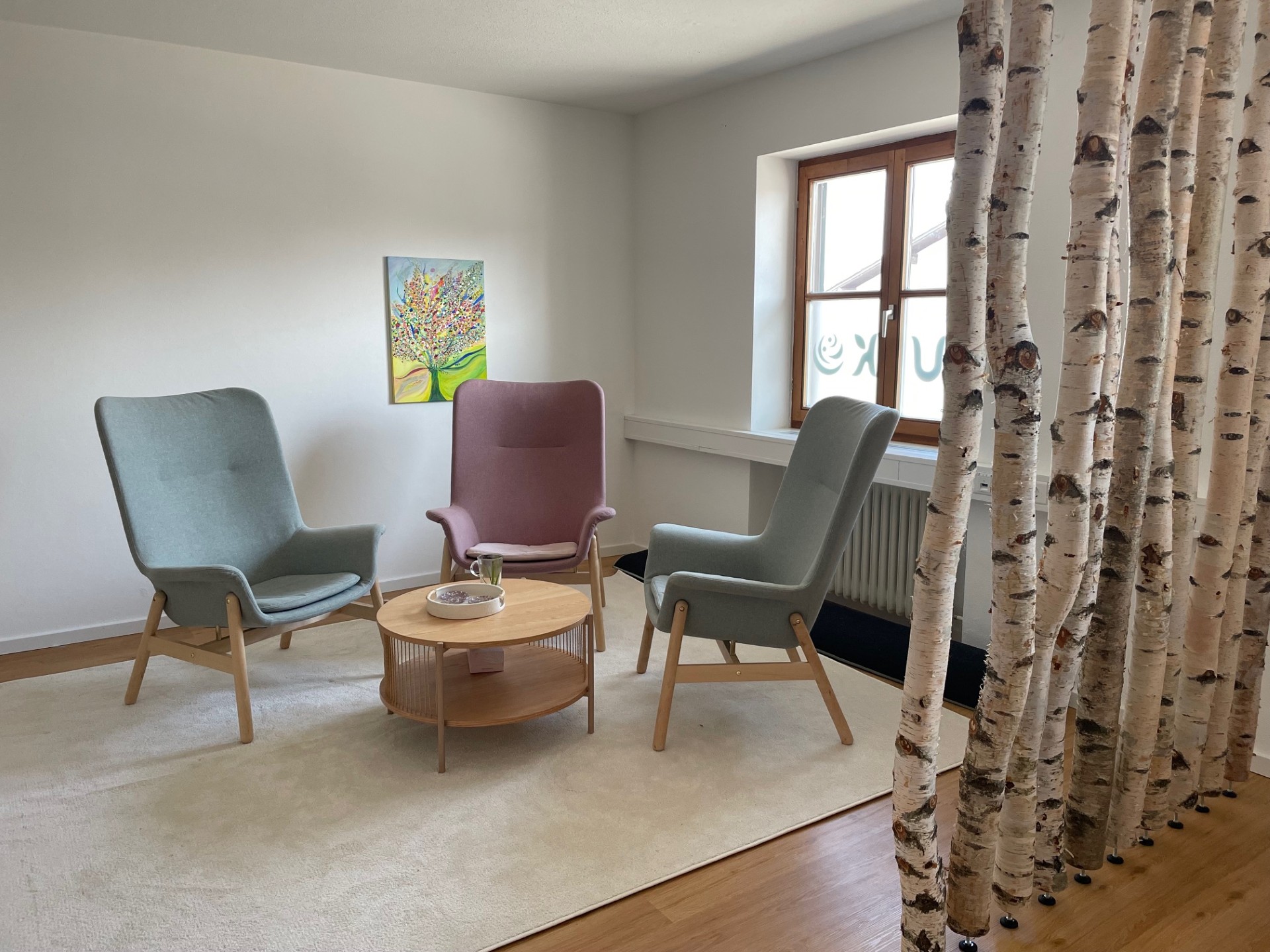 Praxisraum im YUKO-Zentrum in Otterfing mit drei Sesseln und Birkenstämmen